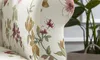 A close-up view of a floral patterned sofa cushion, with a potted plant in the background. Produktbild-Vorschau