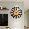 A large wall clock with Roman numerals is mounted on a white brick wall above a television. Produktbild-Vorschau