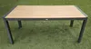 A rectangular outdoor dining table with a slatted wooden top and a dark gray metal frame, set on a green artificial lawn. Produktbild-Vorschau
