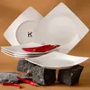 A set of white square plates with red chili peppers on them, arranged on dark rocks. Náhled obrázku produktu