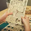 Hands holding a wooden puzzle sheet with various parts, with a partially assembled wooden truck in the background. Náhľad obrázku produktu
