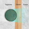 A robot vacuum cleaner is shown on a split background representing different floor types: carpet, wood, and tile. The robot is depicted as being able to clean all three. Produktbild-Vorschau