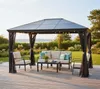 A gazebo with outdoor furniture set up on a wooden deck, with a garden and water in the background. Produktbild-Vorschau
