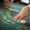 A close-up shot of hands playing cards on a green felt table, with poker chips visible. Produktbild-Vorschau