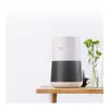 A Winix air purifier is placed on a wooden table next to a vase of green flowers and a small mug. Voir les images du produit