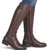 A person wearing brown leather knee-high boots. Voir les images du produit