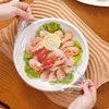 Hands are shown covering a bowl of shrimp with plastic wrap. Produktbild-Vorschau