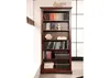 A wooden bookshelf filled with books and decorative items, set against a backdrop of white blinds and a grid-like window panel. Produktbild-Vorschau