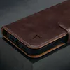 Close-up of a dark brown leather wallet case for an iPhone, showing the embossed logo and the edge of the case. Produktbild-Vorschau