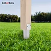 A wooden post is secured in the ground with a metal post anchor, surrounded by green grass and trees in the background. Náhled obrázku produktu
