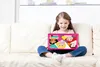 A young girl is sitting on a couch, holding a pink laptop with cartoon characters on the screen. Produktbild-Vorschau
