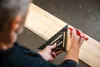 A person is using a triangle ruler to draw lines on a wooden plank. Voir les images du produit