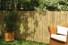 A garden scene with a bamboo fence, a potted plant, and a wicker chair with cushions. Produktbild-Vorschau