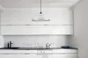 A modern, minimalist kitchen with white cabinets and a black countertop. Produktbild-Vorschau