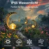 A garden path lined with flowers, with moon-shaped solar lights illuminating the scene during a rain shower. Produktbild-Vorschau