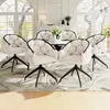 A dining room set with chairs around a table, in a well-lit room with large windows. Produktbild-Vorschau