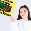 A young woman holds up a yellow metal sign with text and an illustration of firewood. Produktbild-Vorschau