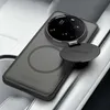 A smartphone case with a camera lens cover is placed on a textured surface, possibly a car seat. Produktbild-Vorschau