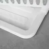 A close-up view of a white plastic dish drying rack on a gray concrete surface. Produktbild-Vorschau