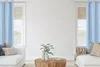 A living room scene with two sofas, a coffee table, and two windows with blue curtains. Produktbild-Vorschau