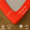 A close-up view of an orange fitted sheet corner, showing its elasticized edge and some text overlays highlighting product features. Produktbild-Vorschau