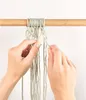 Hands are shown tying macrame knots on light green cords hanging from a wooden dowel. Produktbild-Vorschau