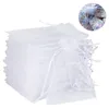 A stack of white organza gift bags with a drawstring closure, with a close-up inset showing the bags filled with colorful confetti. Produktbild-Vorschau