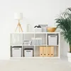 A white shelving unit filled with various storage boxes, books, and decorative items against a white wall. Produktbild-Vorschau