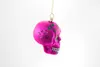 A pink skull-shaped Christmas ornament hangs from a gold string against a white background. Produktbild-Vorschau