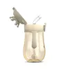 A baby bottle with a straw and a lid decorated with a crown-like design, set against a white background. Produktbild-Vorschau