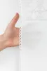 A hand is holding a white lace curtain against a white background. Produktbild-Vorschau