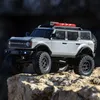 A silver RC car, a replica of a 2021 Ford Bronco, is positioned on a rocky surface, with a blurred dark background. Podgląd zdjęcia produktu