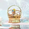 A wooden 3D puzzle of an orrery or celestial model is displayed on a reflective surface, with a soft, ethereal background suggesting a winter or fantasy scene. Voir les images du produit