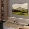A modern living room with a large TV displaying a landscape image, mounted above a stone shelf with a lamp and books. Voir les images du produit