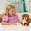 A young girl is playing with a toy monkey, feeding it a bottle. Podgląd zdjęcia produktu