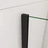 A close-up view of a black profile and a green stabilization rod of a walk-in shower enclosure against a white tiled wall. Produktbild-Vorschau