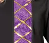 Close-up of a black garment with a purple inset panel decorated with gold criss-cross lacing. Produktbild-Vorschau