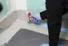 A person is applying a waterproofing compound to the corner of a room. Produktbild-Vorschau
