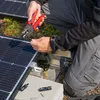 A person is working on installing solar panels, using a tool to crimp a wire. Anteprima dell’immagine prodotto
