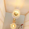 A close-up view of two light bulbs inside a wooden and parchment lamp. Náhled obrázku produktu