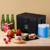 A black cooler box with food and drinks arranged around it. Produktbild-Vorschau