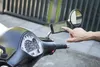 A hand is shown interacting with a smartphone mounted on a scooter's mirror, displaying a navigation app. Anteprima dell’immagine prodotto