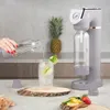 A person is pouring water into a glass of ice and fruit, with a soda maker in the background. Produktbild-Vorschau