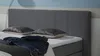 A close-up view of a bed with a headboard, pillows, and a pair of jeans. Produktbild-Vorschau