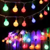 String lights with colorful bulbs are draped over a white picket fence, creating a festive atmosphere. Produktbild-Vorschau