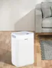 A white dehumidifier is placed on a wooden floor next to a gray sofa and a rug. Anteprima dell’immagine prodotto