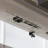 A white wire basket attached to the underside of a desk, holding a black power adapter and some cables. Náhled obrázku produktu