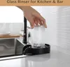 A hand is using a glass rinser attached to a kitchen sink to rinse a glass. Podgląd zdjęcia produktu