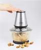 A hand pressing the button on a food chopper with nuts in the bowl and scattered around the base. Produktbild-Vorschau