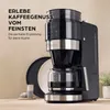A black coffee maker with a grinder and glass carafe is displayed on a counter, with plates and a small cup in the foreground. Produktbild-Vorschau